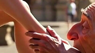 Submissive Man Worshipping Mistress Feet in Public Plaza